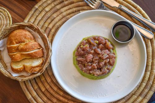 a plate with a bowl of chili and a basket of bread at Badolina Bungalows in Nungwi