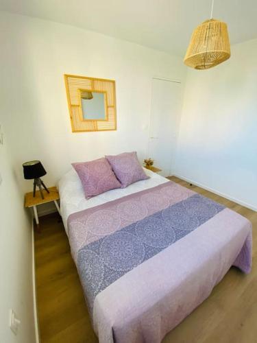 - une chambre dotée d'un lit avec des draps violets et un miroir dans l'établissement Appart cosy Carnon-plage, à Mauguio