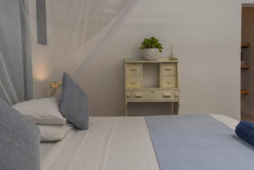 a bedroom with a bed and a dresser with a plant at Badolina Bungalows in Nungwi