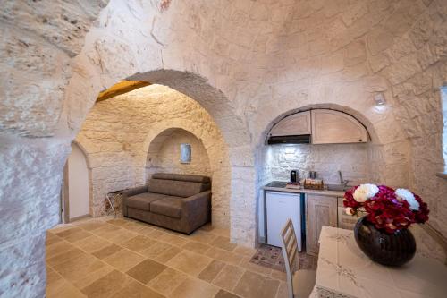 a living room with a couch and a kitchen in a stone wall at Resort Trulli San Leonardo in Alberobello