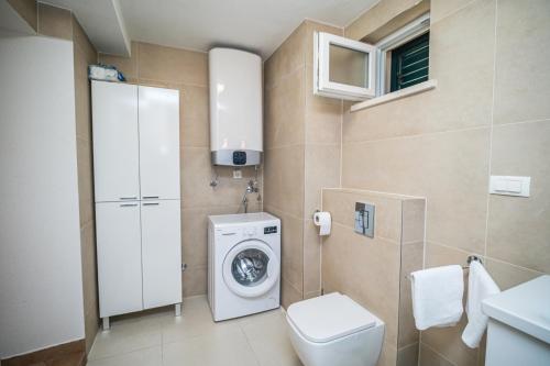 a bathroom with a washing machine and a toilet at Vintage house Kolocep in Koločep