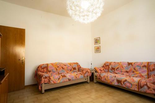 a living room with two couches and a chandelier at Ampio appartamento in Mondolfo