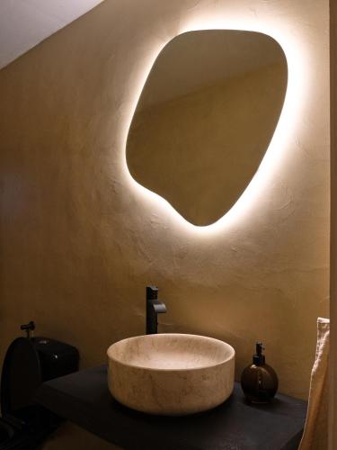 a bathroom with a sink with a large oval mirror at Villa Oraia Verga Kalamata in Kalamata