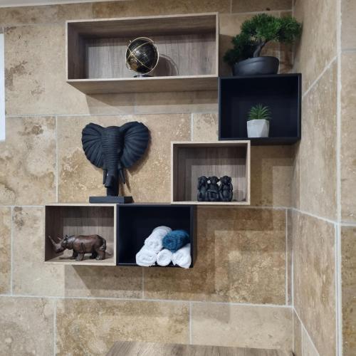 un mur avec des étagères avec des animaux en peluche et une statue dans l'établissement Studio Naturiste Adam Résidence Le Jardin D'Eden, au Cap d'Agde