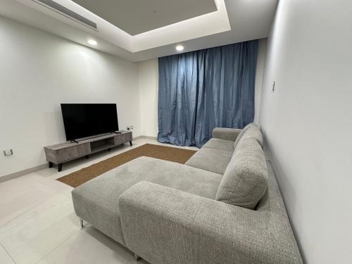 a living room with a couch and a flat screen tv at Pinnacle Row Comfort Corner in Muscat