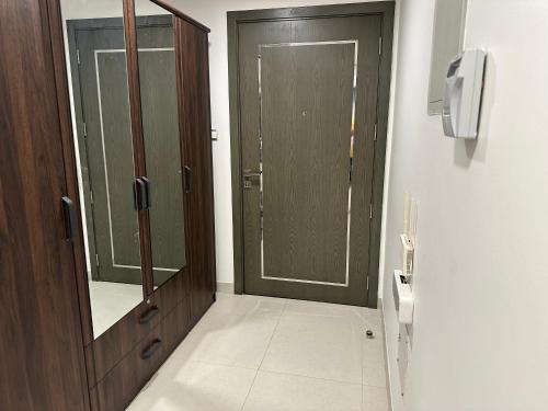 a bathroom with a wooden door and a mirror at Pinnacle Row Comfort Corner in Muscat