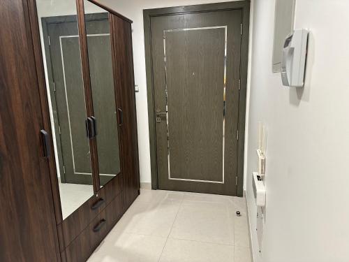 a bathroom with a wooden door and a mirror at Pinnacle Row Comfort Corner in Muscat