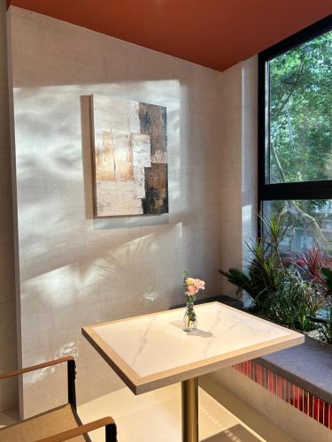 a table in a room with a vase of flowers on it at Mia Hotel - Shanghai Shaanxi South Road in Shanghai
