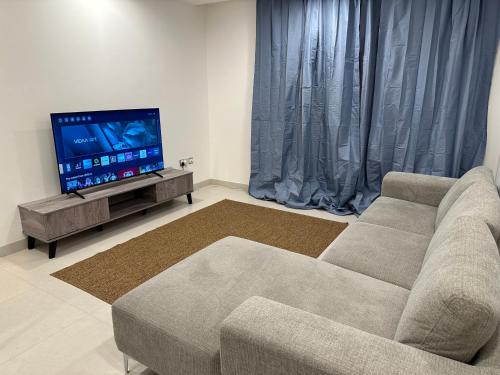 a living room with a couch and a flat screen tv at Pinnacle Row Comfort Corner in Muscat