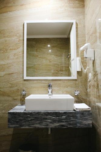 łazienka z białą umywalką i lustrem w obiekcie CLASS Hotel w mieście Ksamil