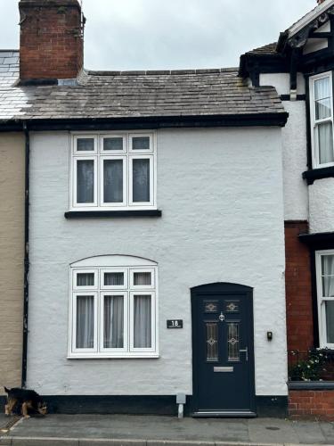 a white house with a dog sitting in front of it at Cottage in Ludlow in Ludlow