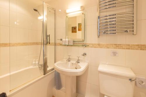 a bathroom with a sink and a toilet and a shower at Oakfold House in Bowness-on-Windermere
