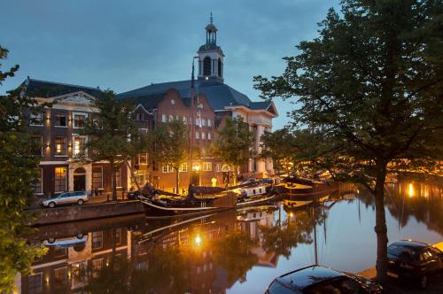 a building with a clock tower next to a river at Vintage Rooms Lange Haven in Schiedam