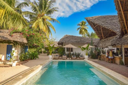 a villa with a swimming pool and palm trees at Badolina Bungalows in Nungwi