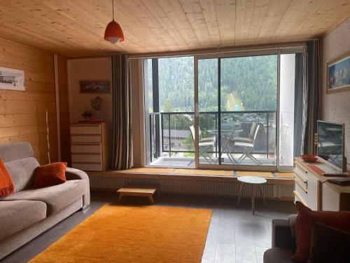 un salon avec un canapé et une grande fenêtre dans l'établissement Plein centre vue panoramique exceptionnelle Sud très grand studio, à Chamonix-Mont-Blanc