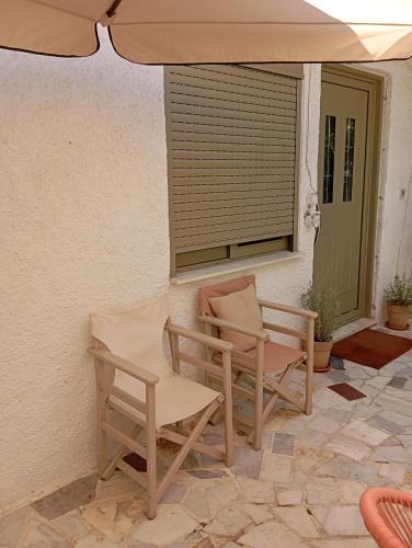 a pair of chairs and an umbrella on a patio at Εξοχικό ROXANI in Ambelákia