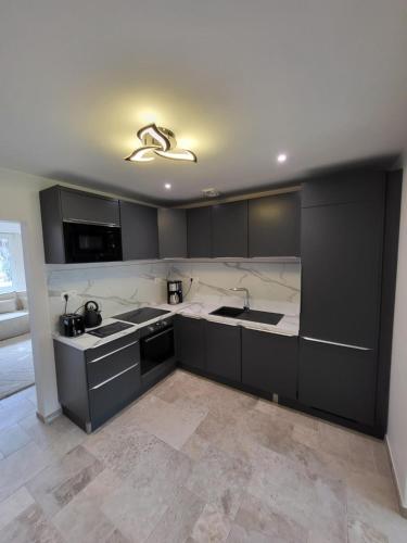 une cuisine avec des armoires noires et des comptoirs blancs dans l'établissement Rode Huis, à Dunkerque