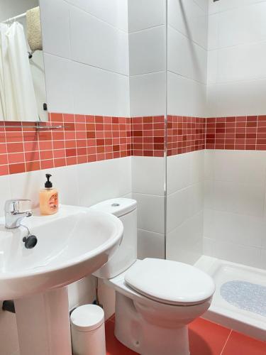a bathroom with a toilet and a sink and a tub at Apartamentos Peñaflor in Guadix