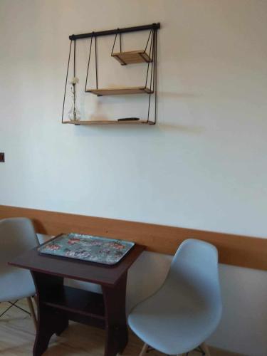 a table with two chairs and a shelf on a wall at Apartament i pokoje na Sosnowej in Ostrowo