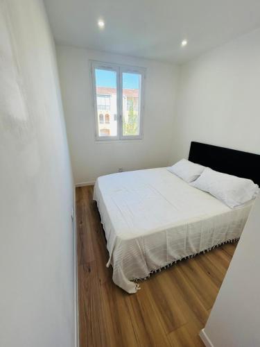 une chambre blanche avec un lit et une fenêtre dans l'établissement Location vacances T2, à Fréjus
