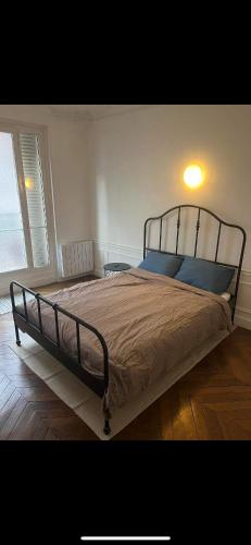 une chambre avec un grand lit avec une lumière dessus dans l'établissement Room in large classic Parisian apartment, à Paris