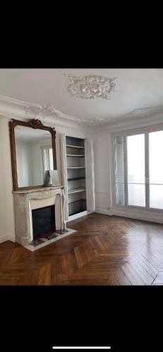 un salon avec une cheminée et un miroir dans l'établissement Room in large classic Parisian apartment, à Paris