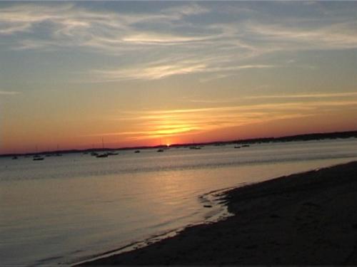 - un coucher de soleil sur la plage avec des bateaux dans l'eau dans l'établissement baletti, à Saint-Vivien-de-Médoc