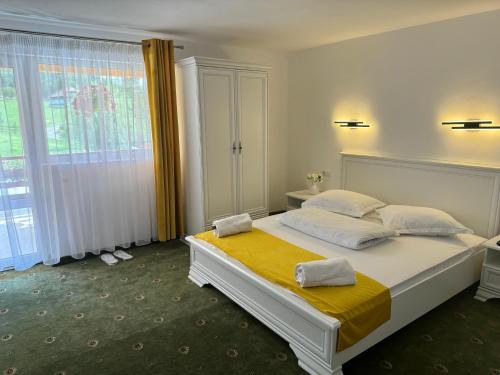 a bedroom with a large white bed with yellow sheets at Pensiunea Mary in Moieciu de Jos