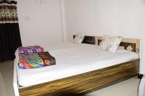 a bed with white sheets and pillows on it at Gurudham Guest house in Ujjain