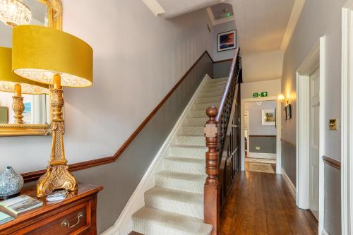 a hallway with a staircase with a lamp and a table at Oakfold House in Bowness-on-Windermere
