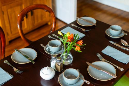 a table with plates and a vase of flowers on it at Oakfold House in Bowness-on-Windermere