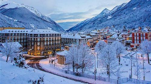 Una ciudad cubierta de nieve con montañas al fondo en Appartement Souplex Centre de Cauterets, en Cauterets