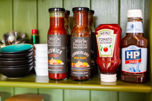 a shelf with three bottles of ketchup and ketchup at Oakfold House in Bowness-on-Windermere