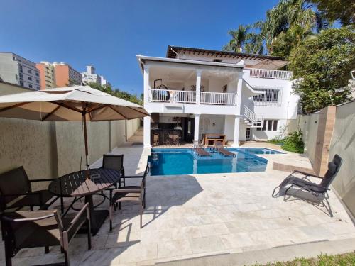 a villa with a swimming pool and a house at Suíte privativa em lindo casarão in Sao Paulo