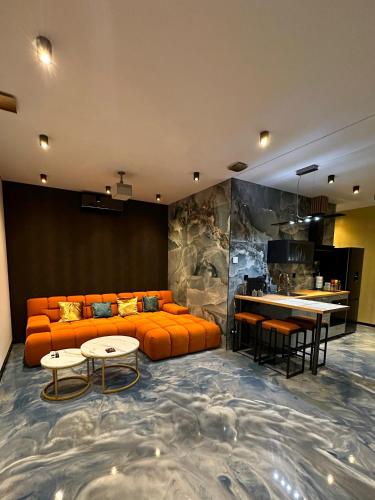 a living room with an orange couch and a table at Luxe appartement dichtbij centrum D in Drachten