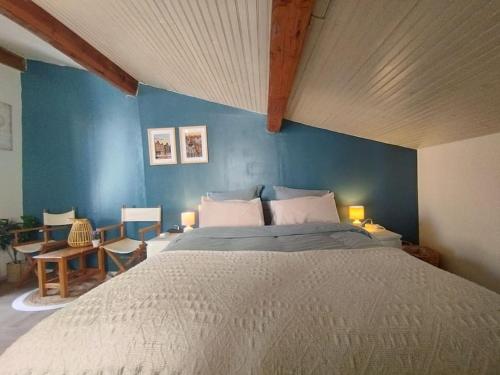 une chambre avec un grand lit avec un mur bleu dans l'établissement Maison Willem, cœur Minervois, à Bize-Minervois