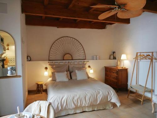 une chambre avec un lit et un ventilateur de plafond dans l'établissement Les Songes d'Augustine, à Aigues-Vives