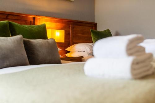 a bedroom with a white bed with a wooden headboard at Oakfold House in Bowness-on-Windermere