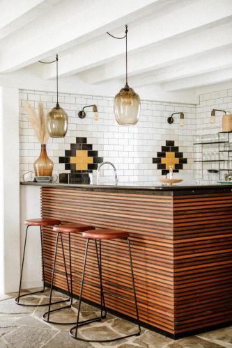a kitchen with two bar stools and a counter with some lights at VILLA Centre Guethary piscine acces ocean a pied in Guéthary