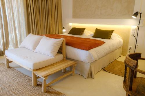 a bedroom with a large bed with a bench next to it at Sorraia Hotel Rural in Santa Justa