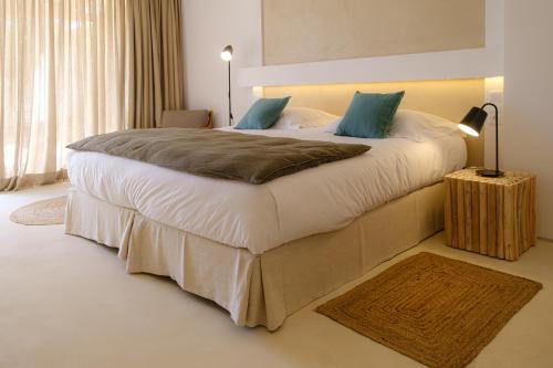 a bedroom with a large bed with white sheets and blue pillows at Sorraia Hotel Rural in Santa Justa