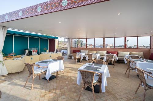 a restaurant with tables and chairs and windows at Riad Atlas Palace & SPA in Marrakech