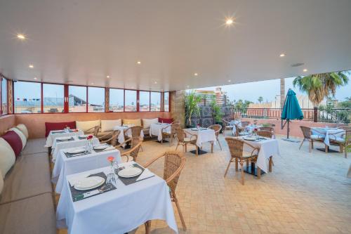 a restaurant with white tables and chairs and windows at Riad Atlas Palace & SPA in Marrakech