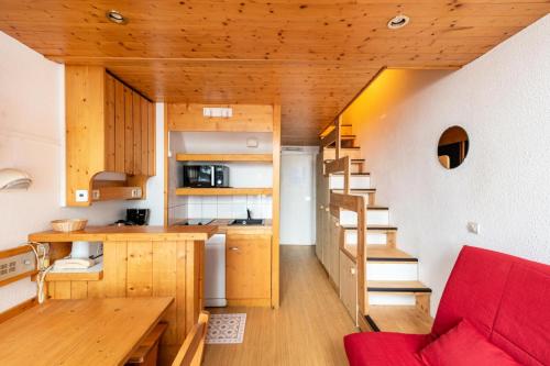 une petite maison avec un canapé rouge et une cuisine dans l'établissement Résidences quartier Charmettoger - maeva Home - Appartement duplex 3 pièces 6 personnes Confort MAE-0814, à Arc 1800