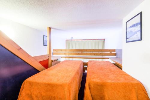 une pièce vide avec 2 lits orange dans l'établissement Résidences quartier Charmettoger - maeva Home - Studio 6 Personnes - Confort MAE-0820, à Arc 1800