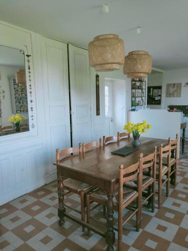 une salle à manger avec une table et des chaises en bois dans l'établissement maison familiale au cœur du cotentin, à Valognes