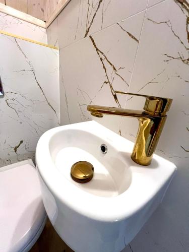 Un baño con un inodoro blanco con grifo dorado. en Bałtycka Strefa, en Władysławowo