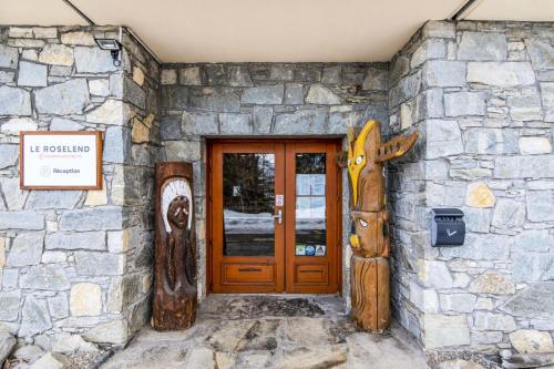 une porte d'entrée d'un bâtiment avec des portes en bois et des statues dans l'établissement Résidence Le Roselend - maeva Home - Appartement 3 Pièces 6 Personnes - Sélection MAE-0982, à Bourg-Saint-Maurice
