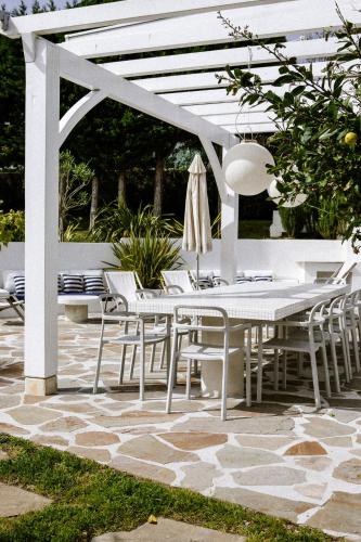 a white pergola with a table and chairs on a patio at VILLA Centre Guethary piscine acces ocean a pied in Guéthary