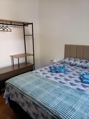 a bedroom with a bed with blue sheets and a table at Pousada Monte Gerizim in Sao Paulo